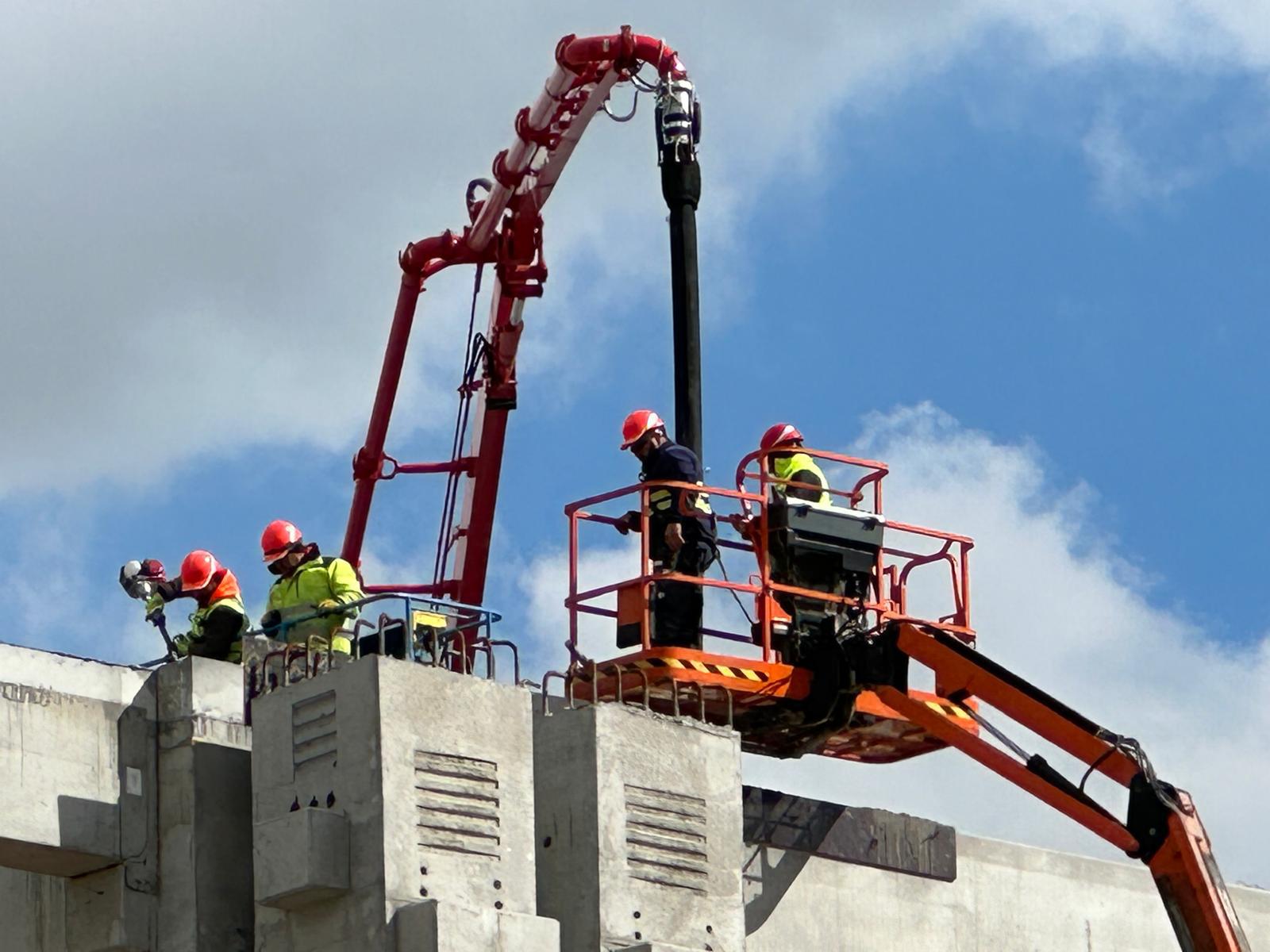 Construction crew pouring concrete with a boom pump on a live building site