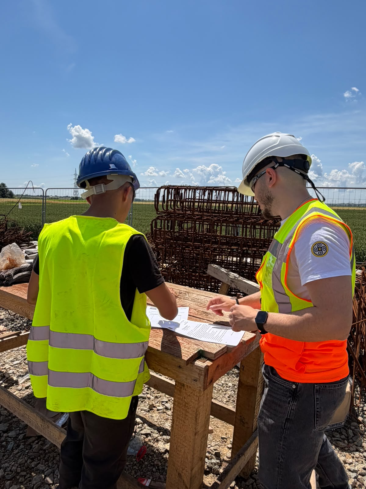 Two Safety Approach specialists reviewing site documentation next to reinforcement cages on a live site